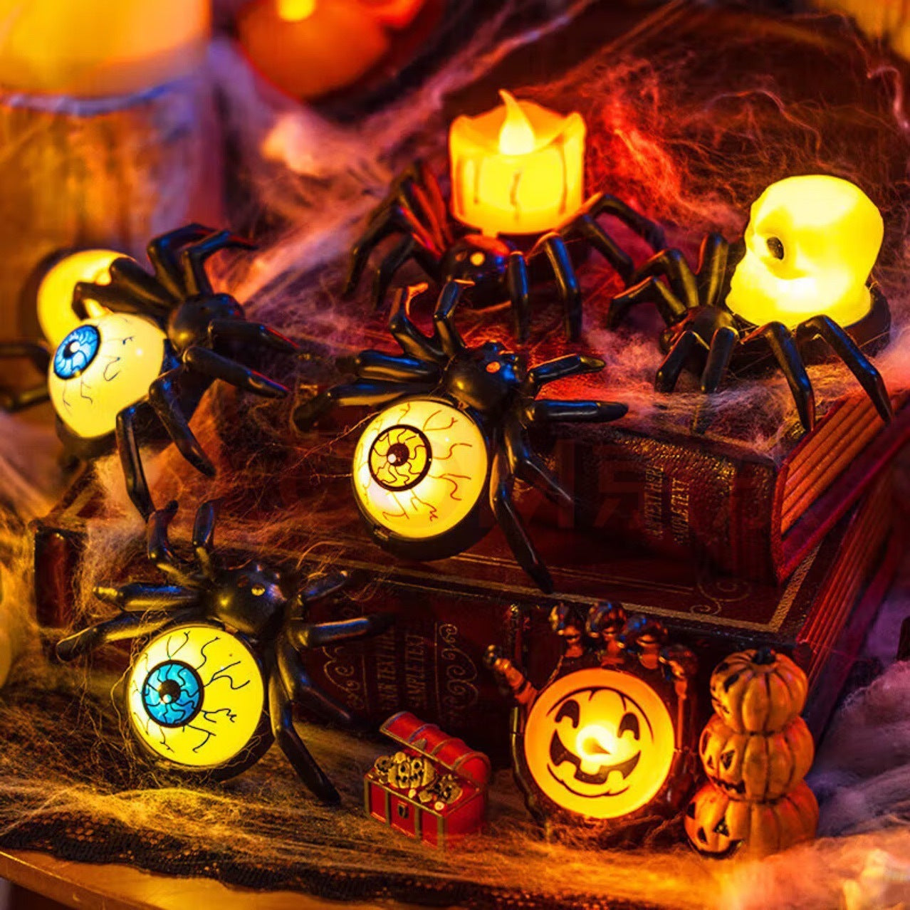 Halloween-themed decorative set with spiders, candles, and pumpkins on a wooden surface.