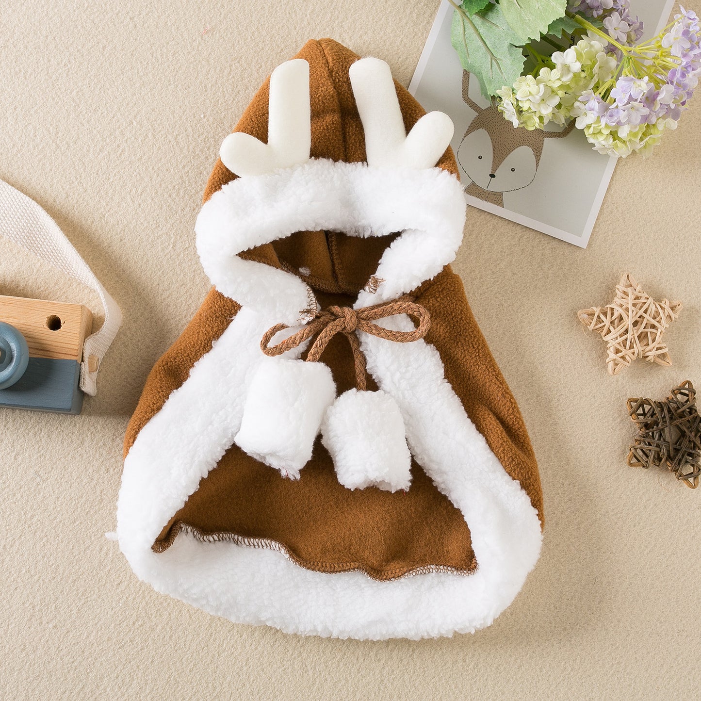 Children's hooded cloak with white fur trim on a beige surface